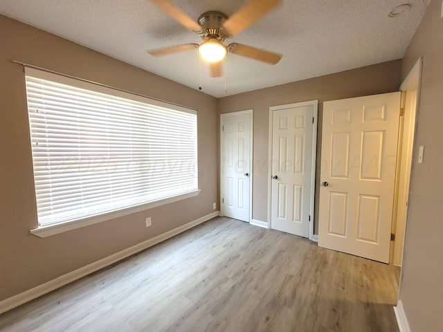 1312 Coffee St, Pampa, TX 79065 - unfurnished bedroom with a textured ceiling, multiple closets, ceiling fan, and light hardwood / wood-style flooring