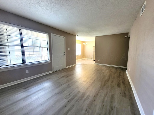 1312 Coffee St, Pampa, TX 79065 - empty room with dark hardwood / wood-style flooring, a textured ceiling, and a notable chandelier