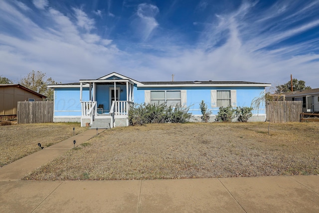 manufactured / mobile home featuring covered porch, solar panels, and a front yard