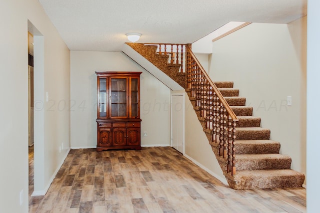 staircase with hardwood / wood-style flooring and a textured ceiling