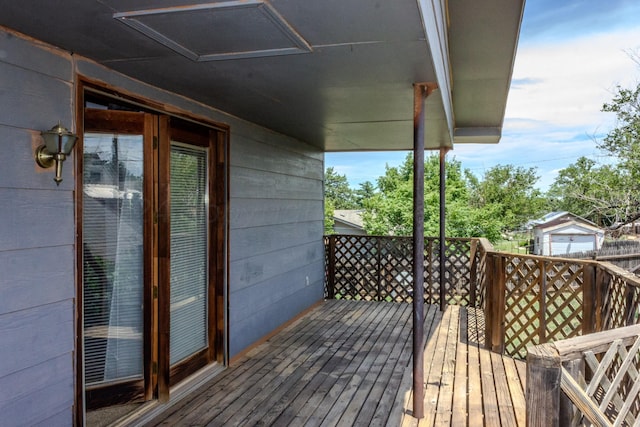 wooden terrace featuring a garage and an outbuilding