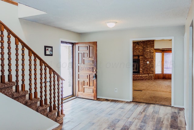 entrance foyer with a fireplace, hardwood / wood-style floors, a healthy amount of sunlight, and a textured ceiling