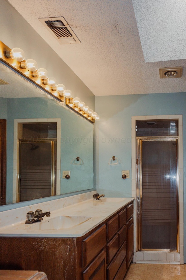 bathroom featuring vanity, a textured ceiling, tile patterned floors, and an enclosed shower