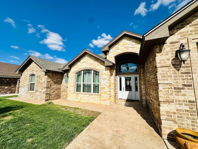 901 Melinda Ln, Dumas, TX 79029 - property entrance featuring a yard, brick siding, stone siding, and a shingled roof