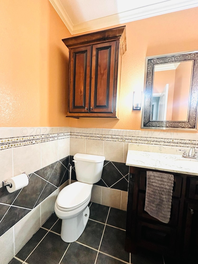 bathroom with tile patterned flooring, toilet, vanity, tile walls, and ornamental molding