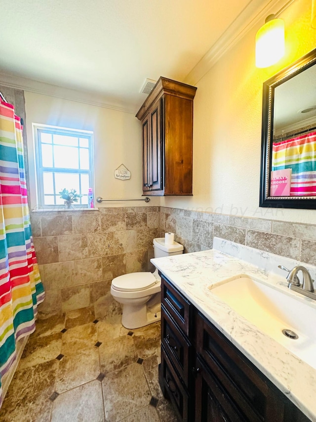 bathroom featuring a shower with shower curtain, ornamental molding, vanity, tile walls, and toilet
