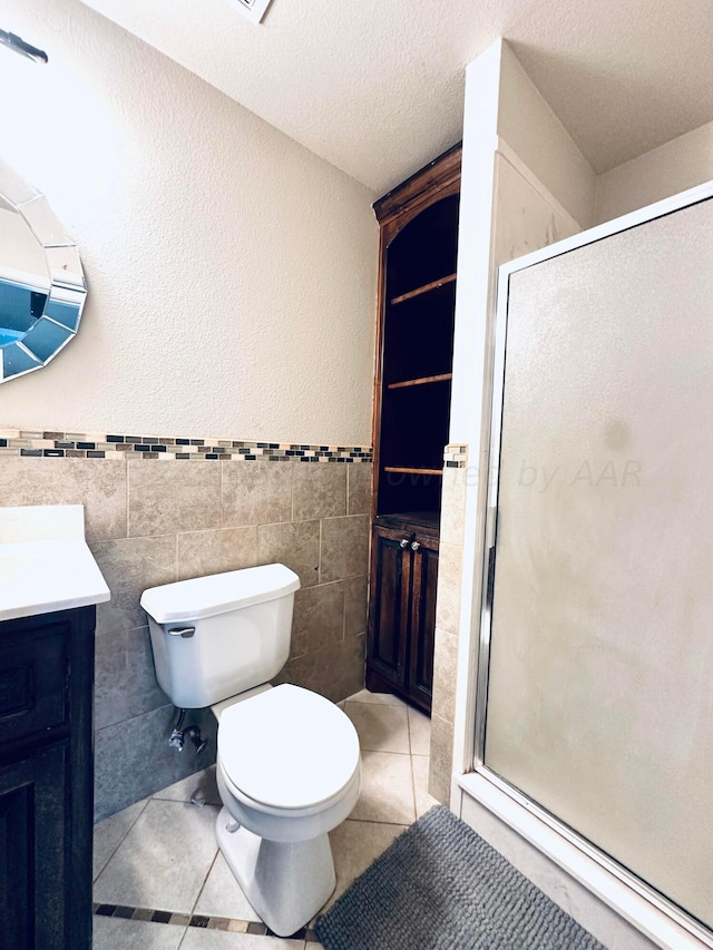 bathroom featuring walk in shower, tile patterned floors, a textured ceiling, toilet, and tile walls