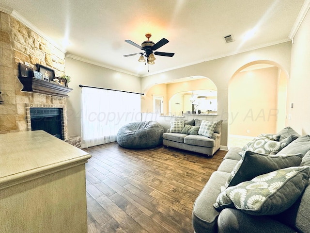 living room with a fireplace, dark hardwood / wood-style floors, ceiling fan, and crown molding