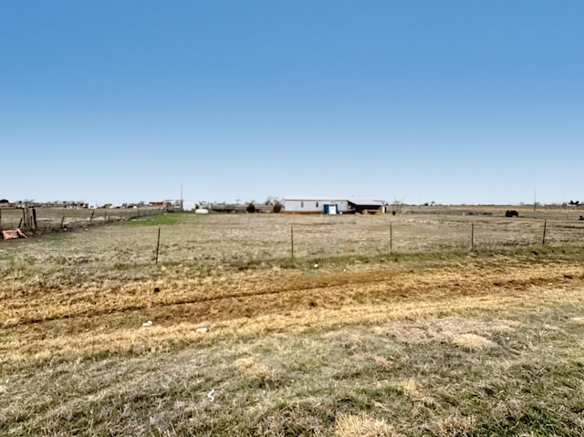 view of yard with fence and a rural view