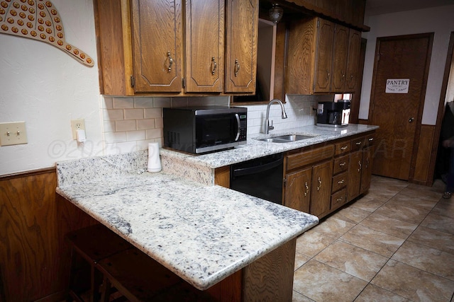 kitchen with dishwasher, light stone countertops, sink, and a breakfast bar area