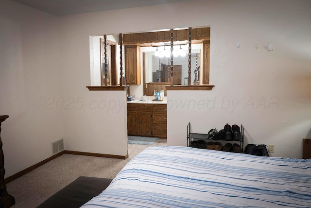bedroom with ensuite bath and light carpet