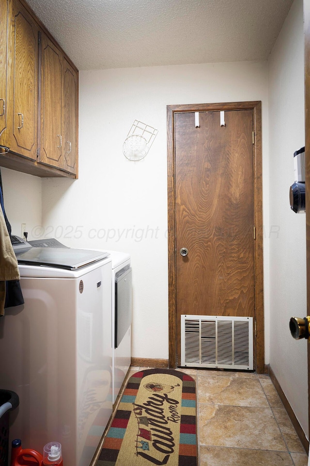 laundry room featuring cabinets, independent washer and dryer, and a textured ceiling