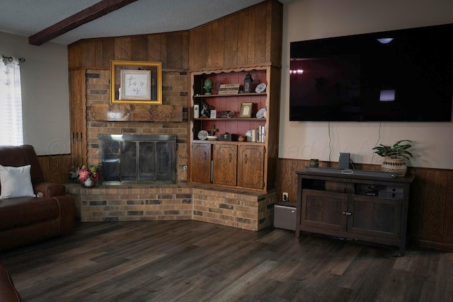 living room with beamed ceiling, dark hardwood / wood-style flooring, a brick fireplace, and wood walls