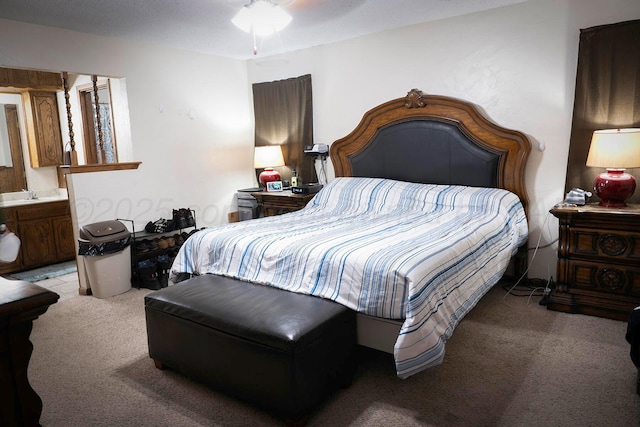 bedroom featuring ensuite bathroom, sink, and light carpet