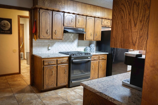 kitchen with black fridge, light tile patterned floors, backsplash, and range with gas cooktop