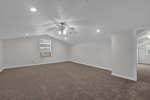 additional living space with ceiling fan, dark carpet, lofted ceiling, baseboards, and cooling unit