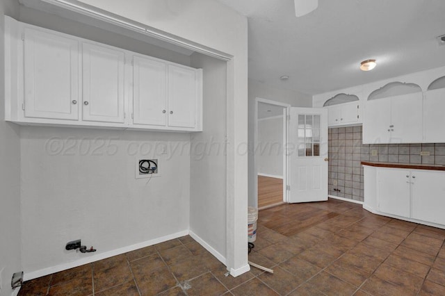 laundry area featuring gas dryer hookup, baseboards, and cabinet space