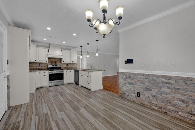 kitchen with gas range, a peninsula, black dishwasher, premium range hood, and a sink