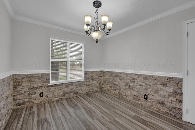 spare room with wainscoting, a chandelier, and crown molding