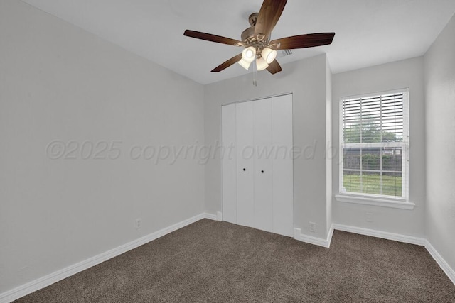 unfurnished bedroom with dark colored carpet, a closet, baseboards, and ceiling fan