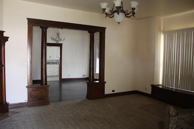 unfurnished room featuring visible vents, baseboards, dark colored carpet, an inviting chandelier, and ornate columns