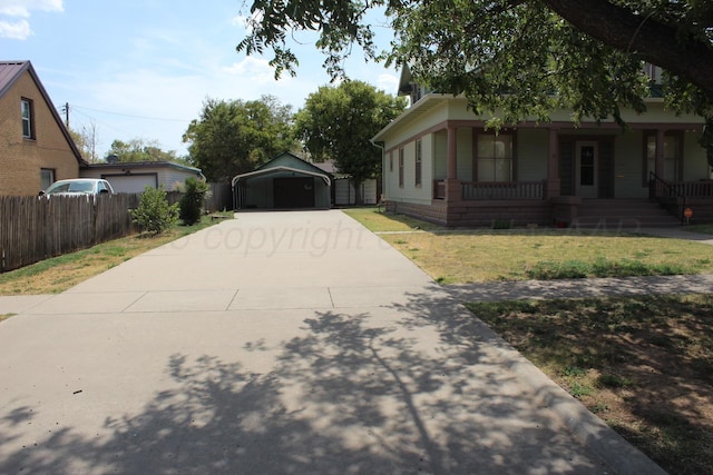 view of side of home with covered porch, fence, a carport, and a yard