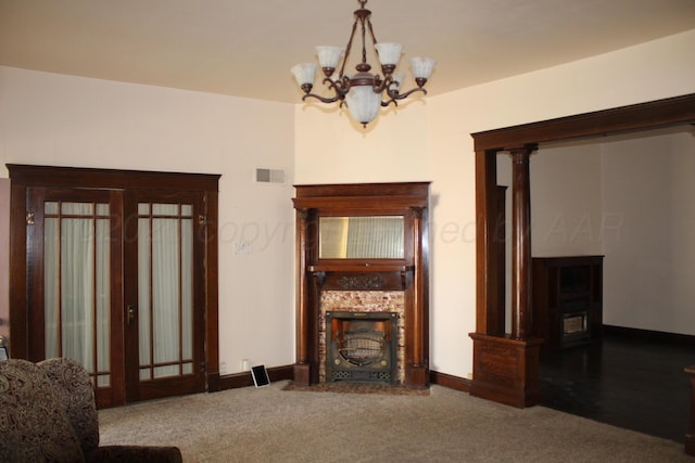 carpeted living room featuring baseboards, visible vents, a chandelier, and a tiled fireplace