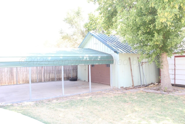 view of outdoor structure featuring a garage, fence, and an outbuilding