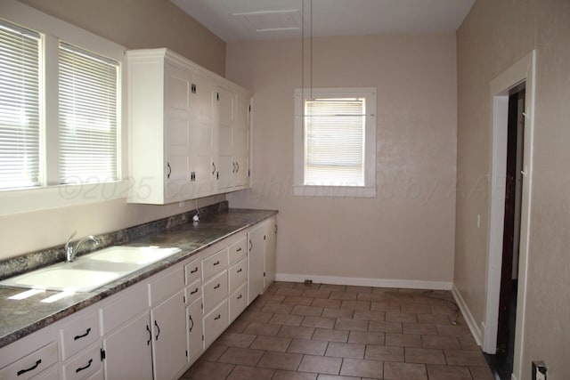 kitchen with tile patterned flooring, a sink, white cabinetry, and baseboards