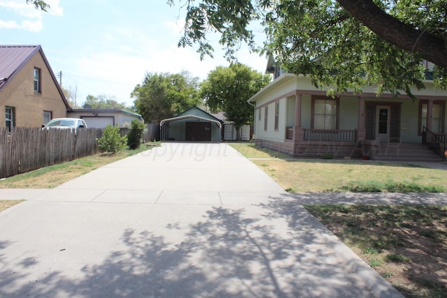 view of front of home featuring driveway, covered porch, fence, a carport, and a front yard