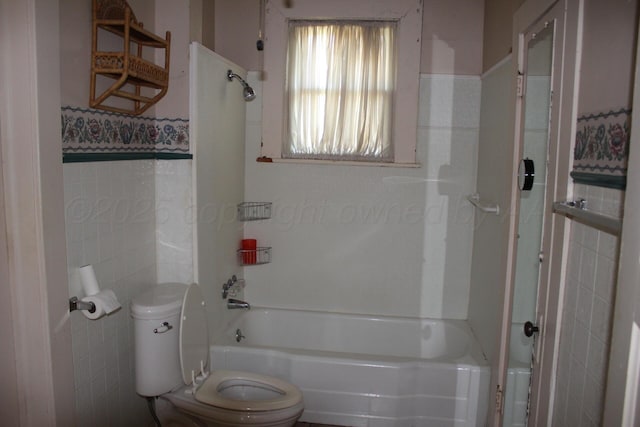 bathroom with shower / washtub combination, tile walls, and toilet