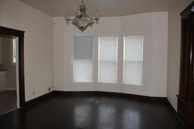 unfurnished dining area featuring a chandelier, dark wood-type flooring, and baseboards