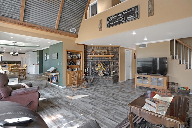 living room featuring a towering ceiling, a brick fireplace, and hardwood / wood-style flooring