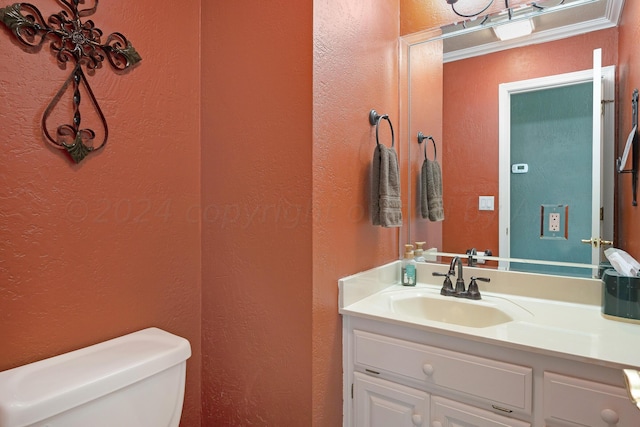 bathroom with toilet, vanity, and crown molding