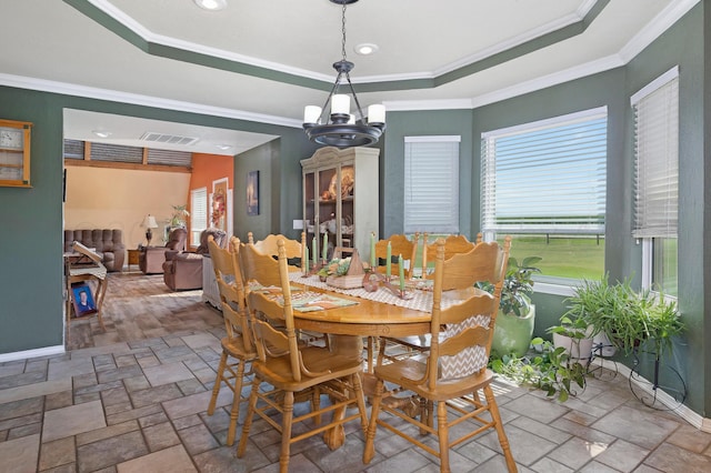 dining space with a healthy amount of sunlight, ornamental molding, and a raised ceiling