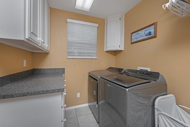 laundry area with washing machine and dryer, cabinets, and light tile patterned floors