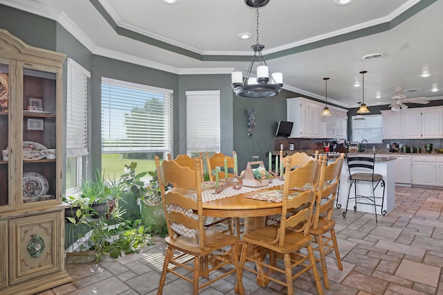 dining room featuring ceiling fan with notable chandelier, a tray ceiling, crown molding, and sink