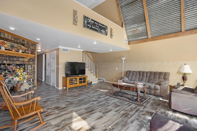 living room with a towering ceiling, a large fireplace, and hardwood / wood-style flooring