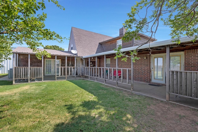 back of property with a lawn, a patio area, and a sunroom