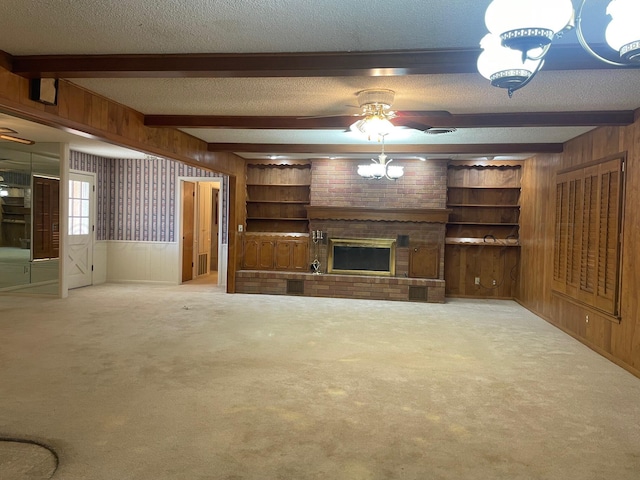 unfurnished living room with beamed ceiling, ceiling fan, a textured ceiling, and wooden walls