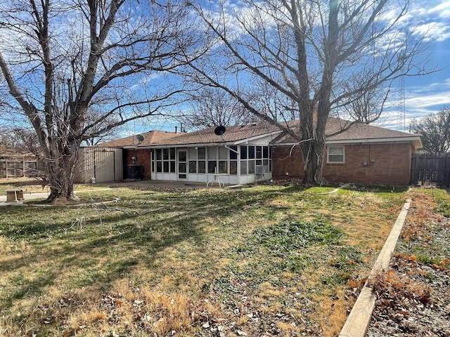 rear view of property featuring a sunroom and a lawn