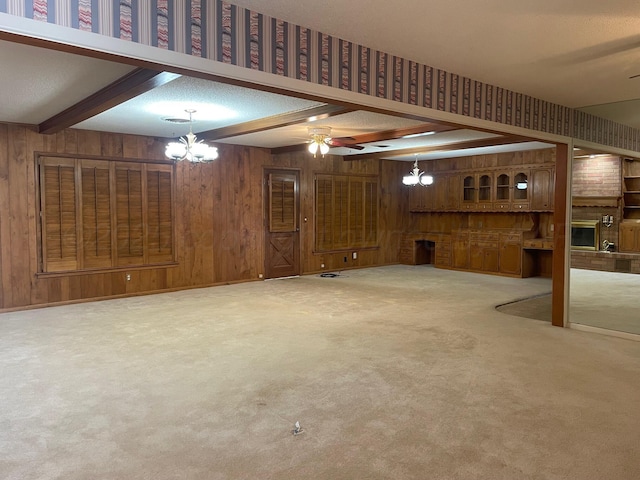 unfurnished living room with carpet flooring, beam ceiling, a textured ceiling, and wooden walls