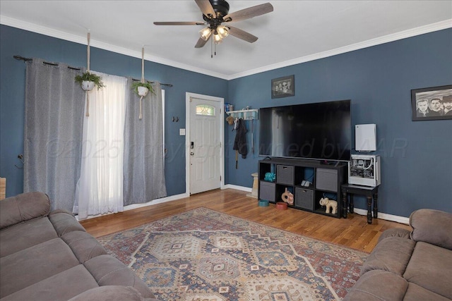 living room featuring baseboards, a ceiling fan, crown molding, and wood finished floors