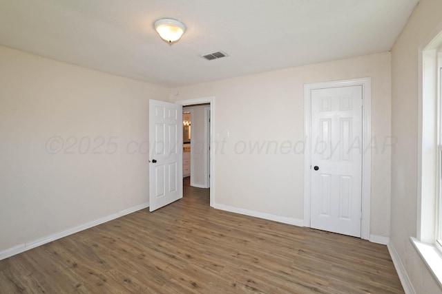 unfurnished room with visible vents, baseboards, and wood finished floors