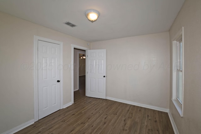 unfurnished bedroom with baseboards, visible vents, and wood finished floors