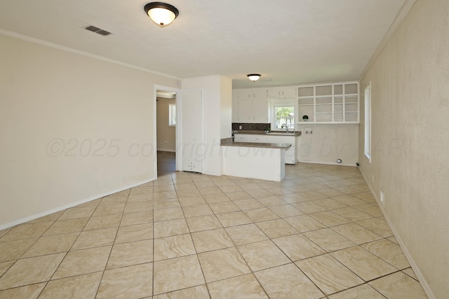 unfurnished living room featuring light tile patterned floors, baseboards, crown molding, and visible vents