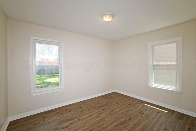 unfurnished room with baseboards, dark wood-style flooring, and a healthy amount of sunlight