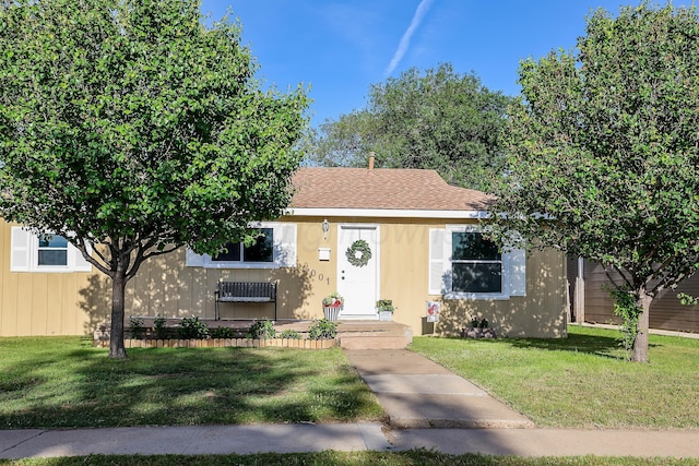 view of front facade with roof with shingles and a front lawn