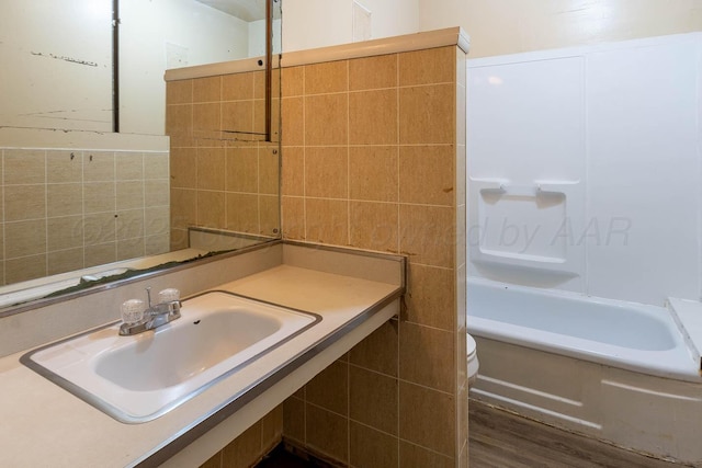 2414 Orange St, Amarillo, TX 79107 - bathroom featuring tile walls, toilet, vanity, shower / washtub combination, and wood finished floors