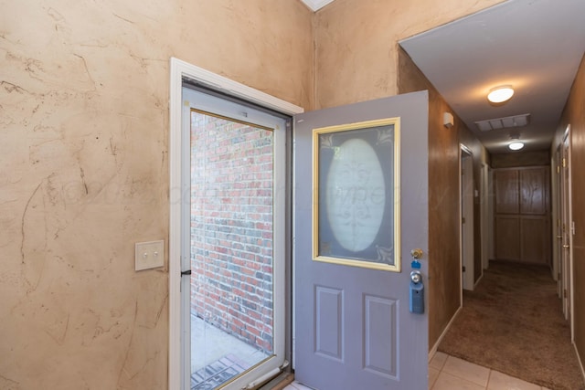 foyer entrance with light tile patterned floors, visible vents, and light carpet